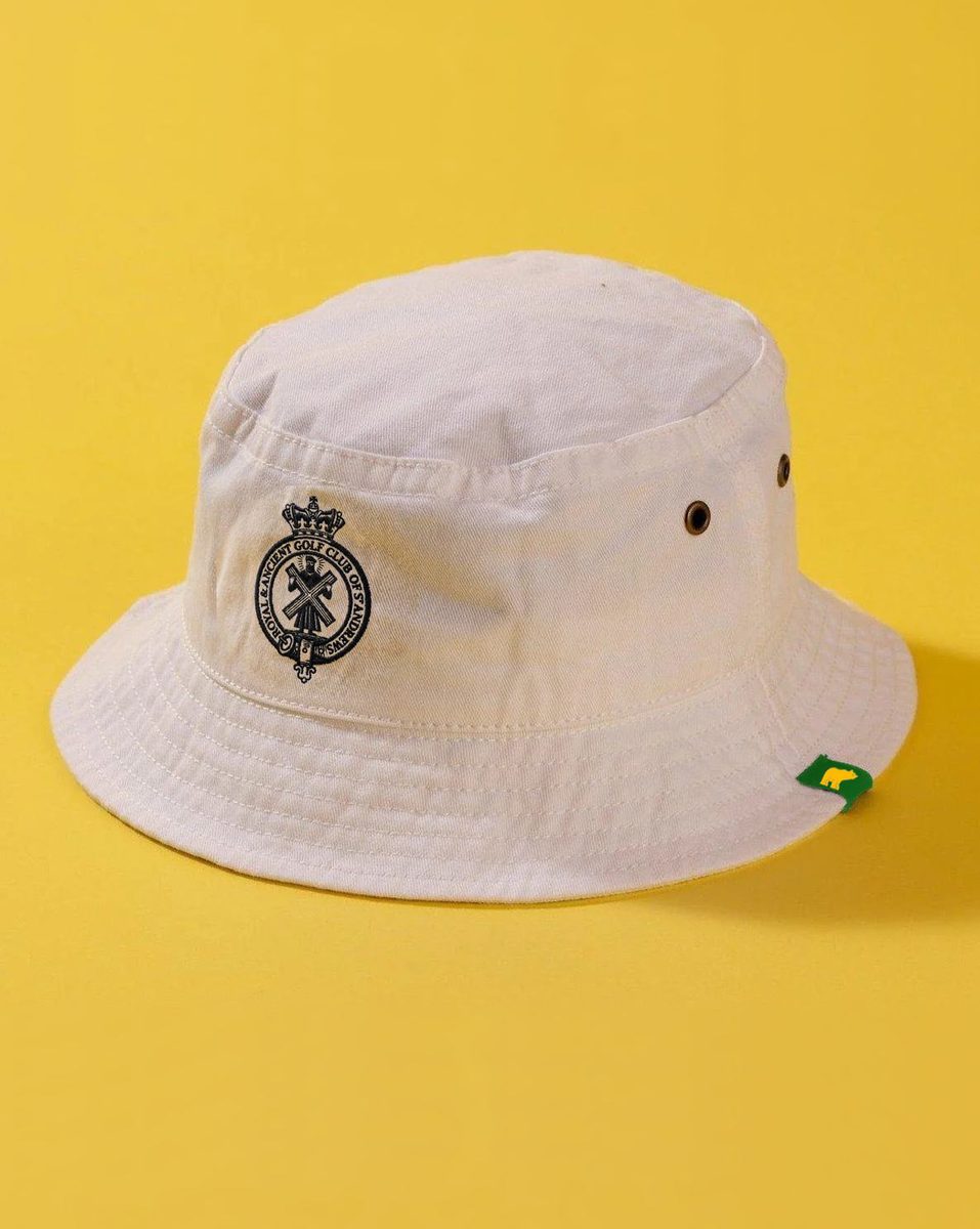 Cream canvas bucket hat up close with embroidered course crest, on a yellow background