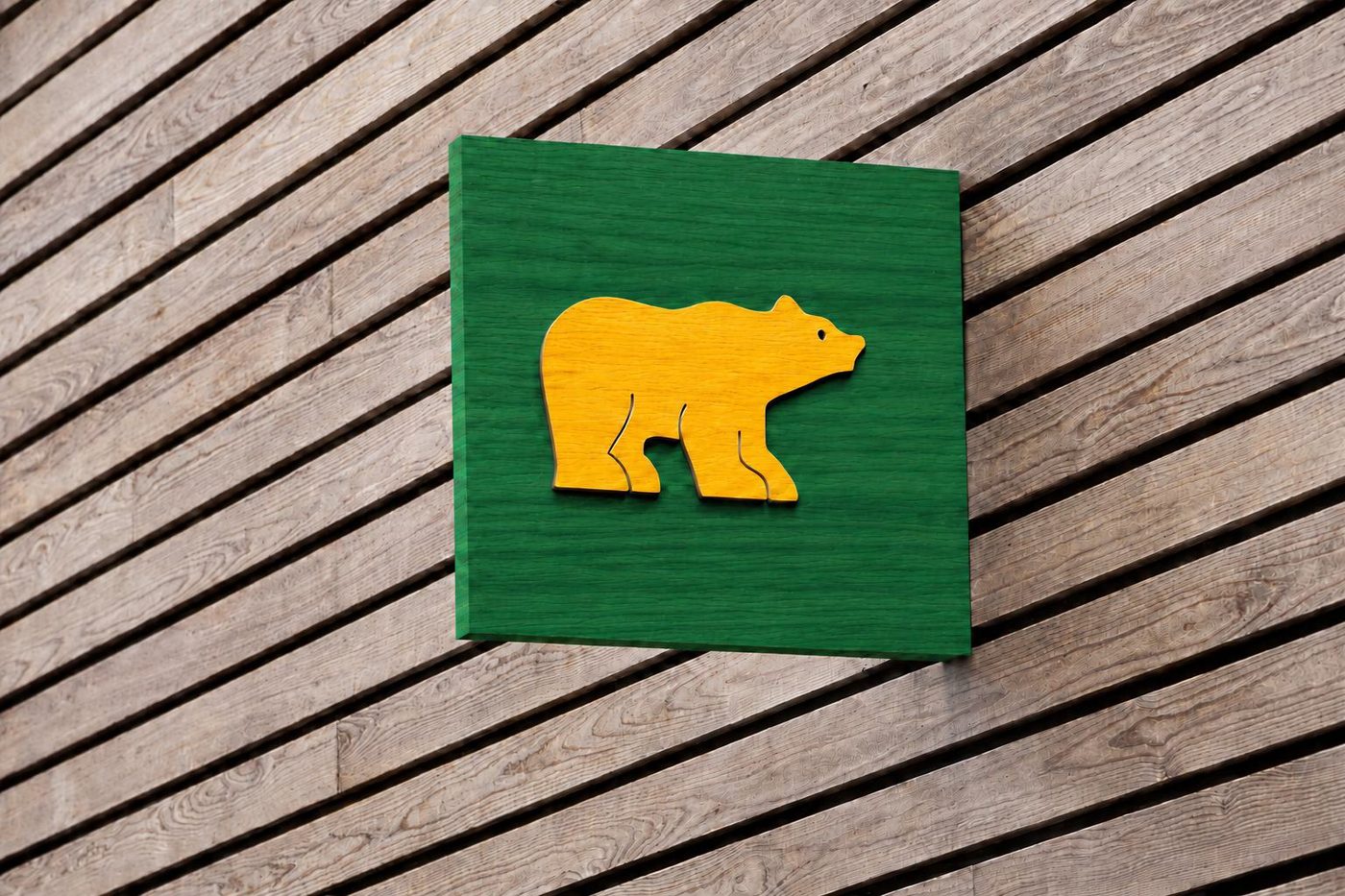 Carved gold Golden Bear on a kelly green panel mounted to a wood slat storefront